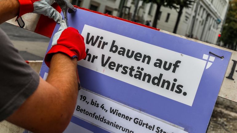 Arbeiter bringt eine Baustelleninformation an