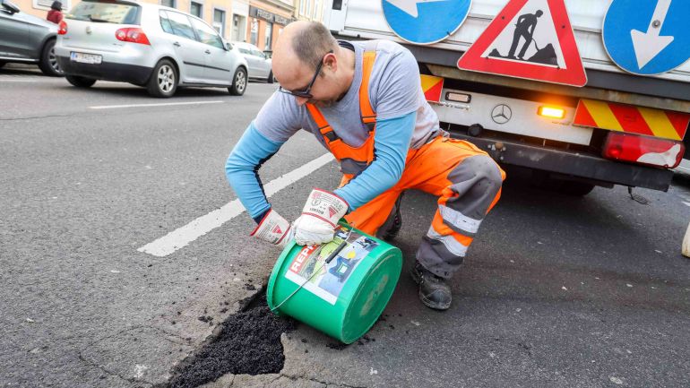 Mitarbeiter füllt ein Schlagloch auf