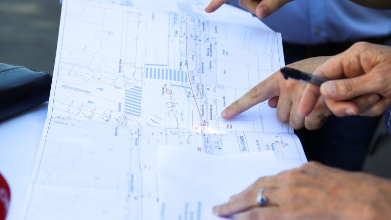 Mehrere Hände zeigen auf eine Planskizze