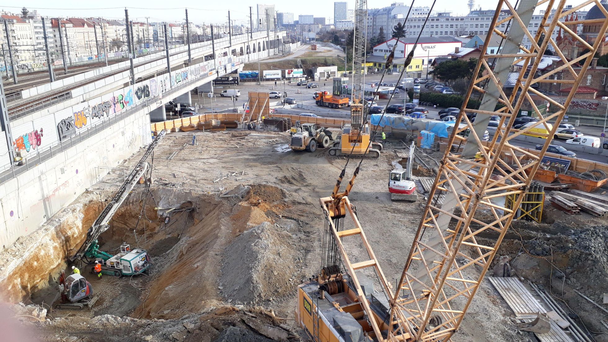 U-Bahnbaustelle mit aufgegrabenem Boden, Kränen und zu verlegenden Rohren