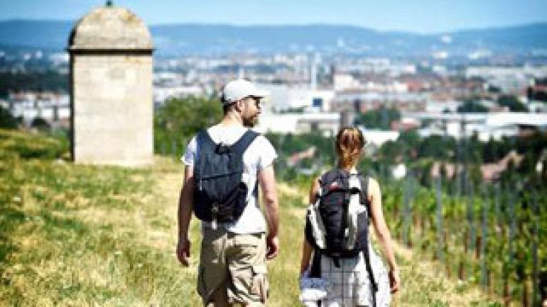 Mann und Frau wandern neben Weinstöcken