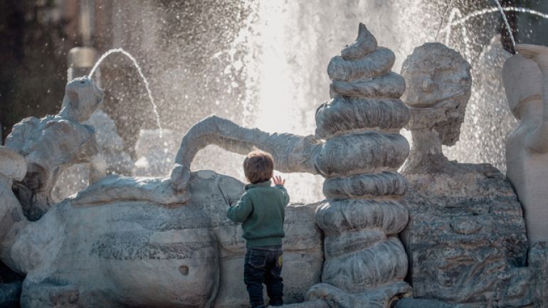 copyright: Michael Eisner Eine kleiner Bub steht vor einem kunstvoll gestaltetem Springbrunnen mit verschnörkelten Figuren