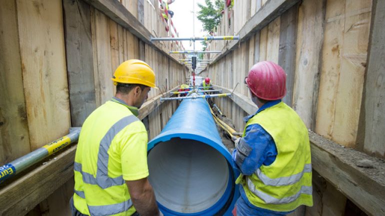 2 Mitarbeiter von Wiener Wasser ziehen ein neues Rohr in ein altes Rohr ein