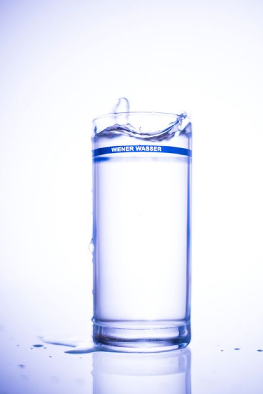 Hohes Wasserglas mit schmaler blauer Umrandung und Schriftzug "Wiener Wasser"