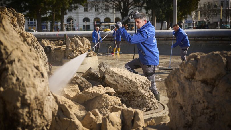 Ein Arbeiter reinigt das ausgeleerte Becken des Hochstrahlbrunnens.