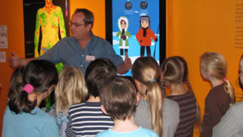 Ein Museumsführer erklärt einer Kindergruppe etwas.