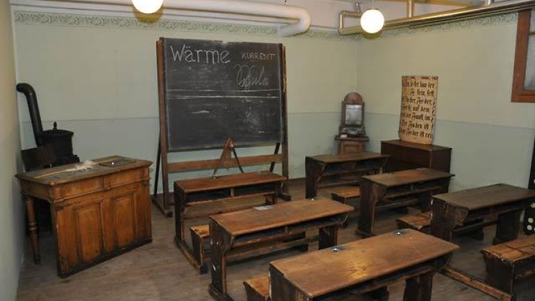 copyright: MA 34 - Bau- und Gebäudemanagement Antiquated schoolroom with desks and black board.