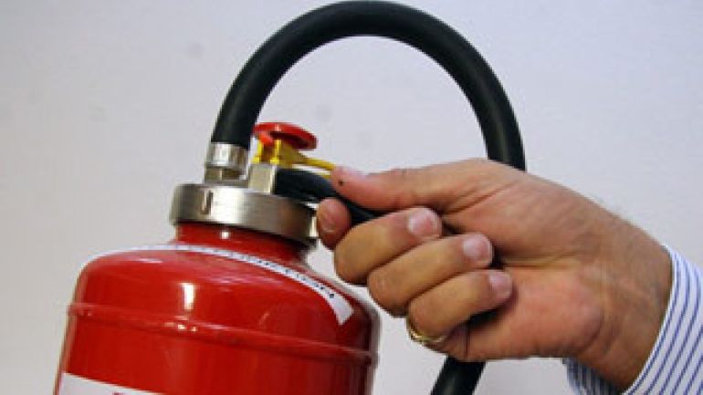 Eine Hand am Ventil eines Feuerlöschers