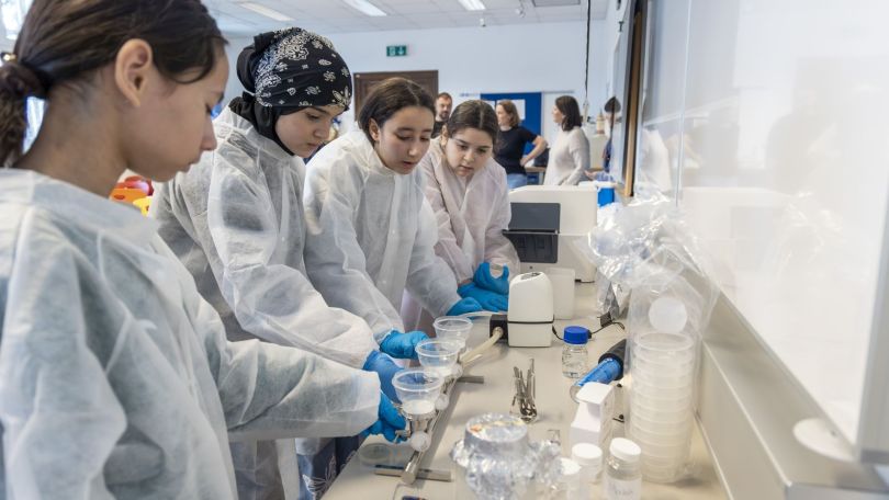 Mädchen in Schutzkleidung arbeiten mit Reagenzgläsern in einem Labor.