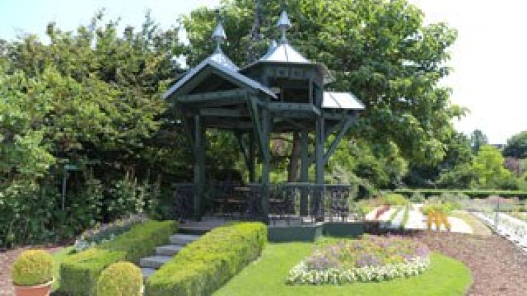 Metallpavillon, von Blumenbeeten umgeben