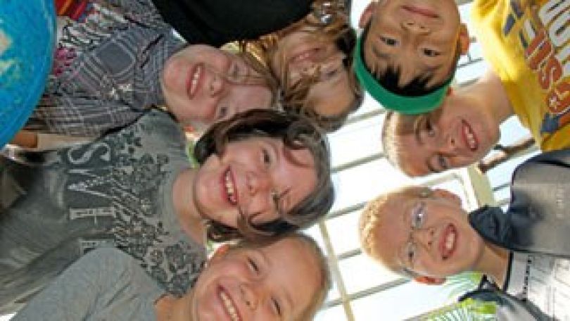 Lachende Kinder blicken von oben in eine Kamera.