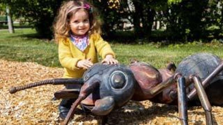 Mädchen mit einer großen Ameise aus Holz