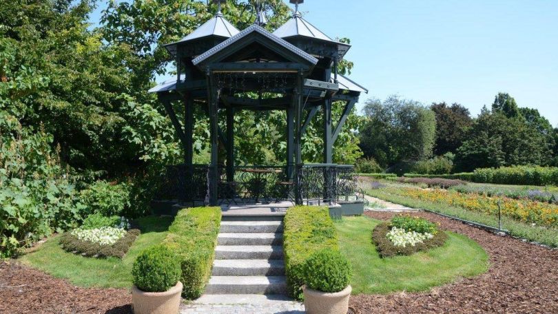 Metallpavillon, von Blumenbeeten umgeben