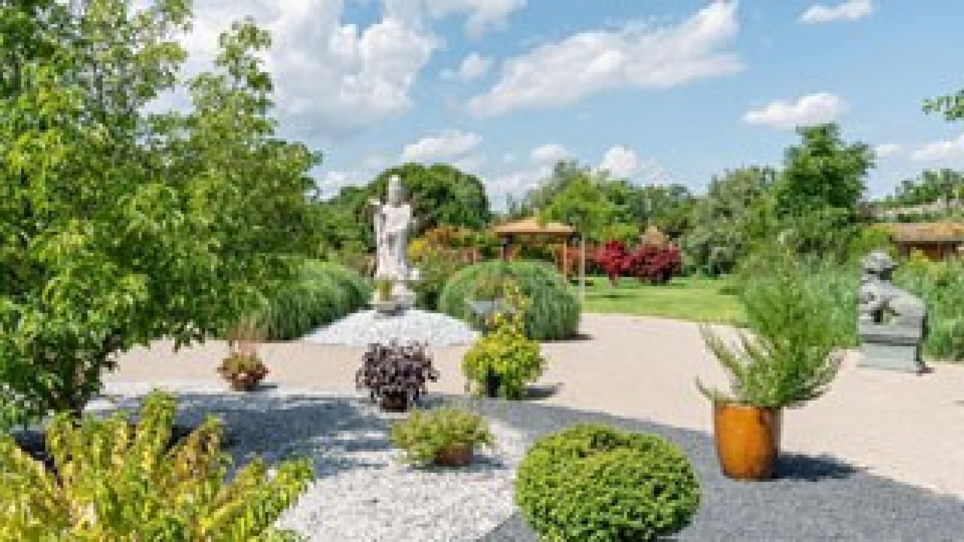 Garten mit Steinen, Bäumen und chinesischen Statuen