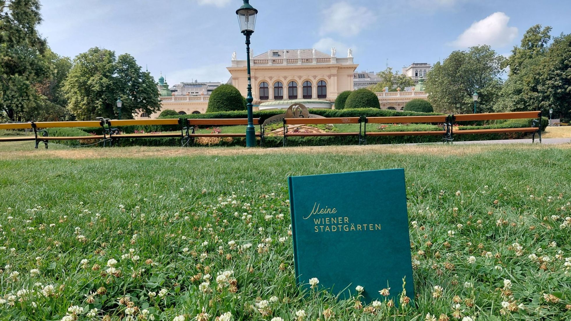 copyright: Wiener Stadtgärten (MA 42) Buch "Meine Wiener Stadtgärten" in der Wiese vor einem historischen Gebäude