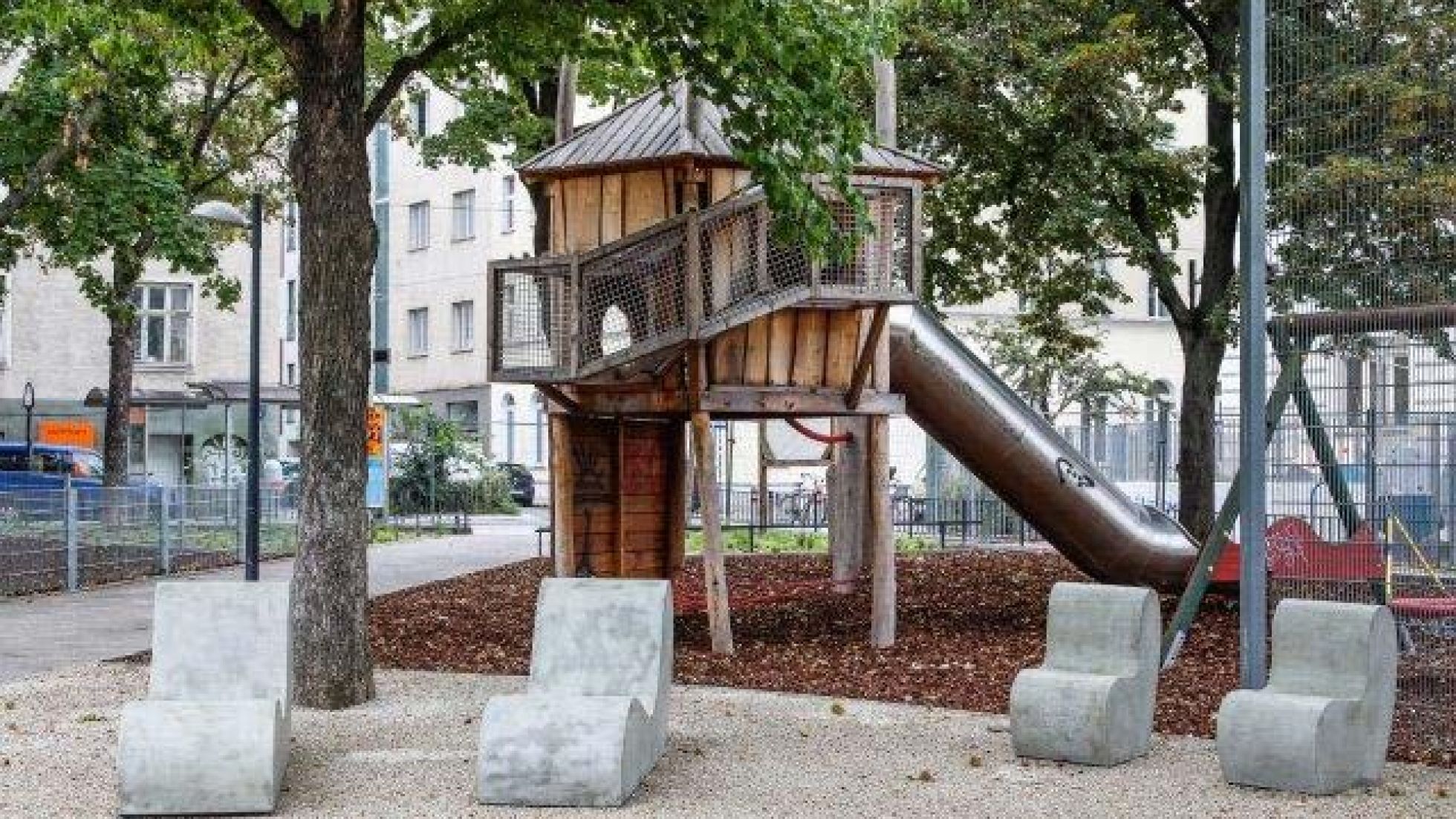 Spielgeräte aus Holz, davor Sitzgelegenheiten aus Stein