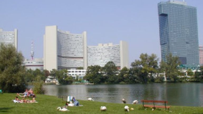 Lagerwiese mit Schwänen, See, dahinter Hochhäuser