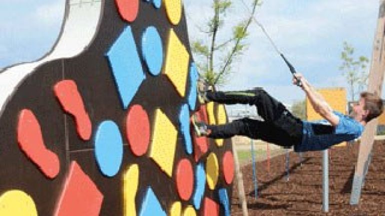 Bub hängt am Seil an einer Kletterwand