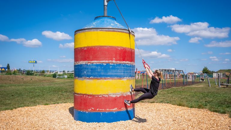 Ein Mann hängt an einem Seil an einem großen bunten Zylinder