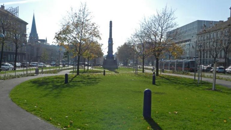 Wiese, geschwungene Wege, im Hintergrund eine Säule