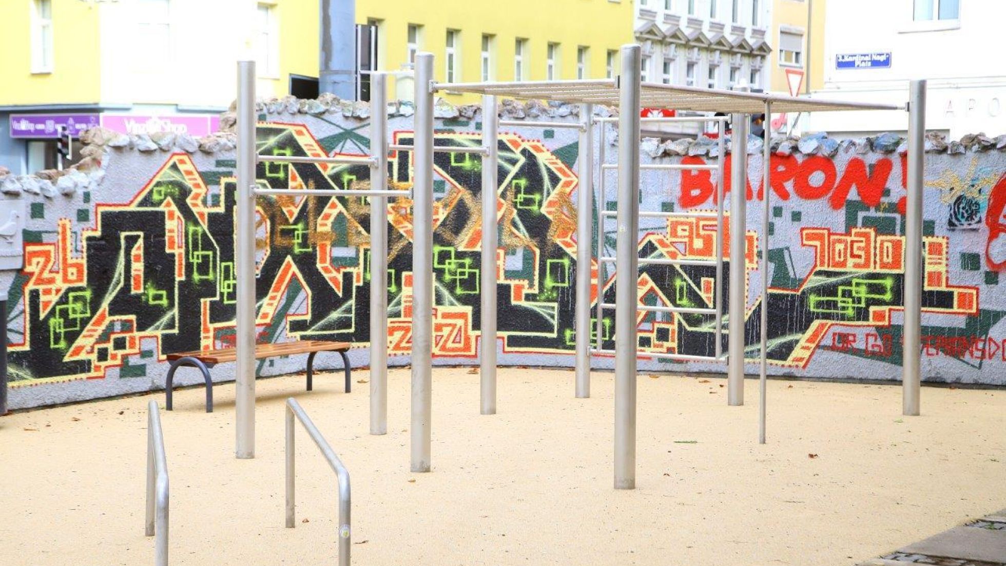 Calisthenics-Anlage, dahinter eine Wand mit Graffiti