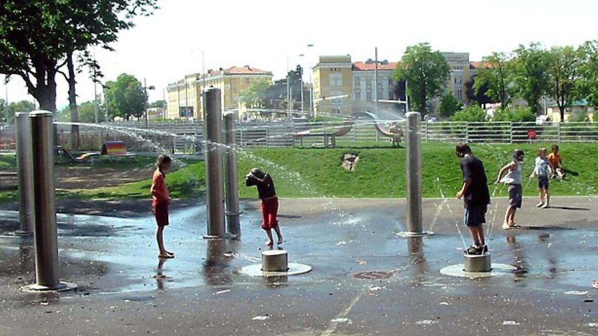 Kinder spielen unter wasserspeienden Säulen