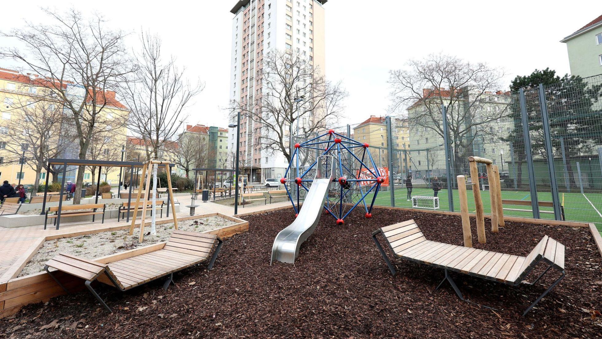 Rutsche, Klettergerüst und Holzliegen auf einem Spielplatz