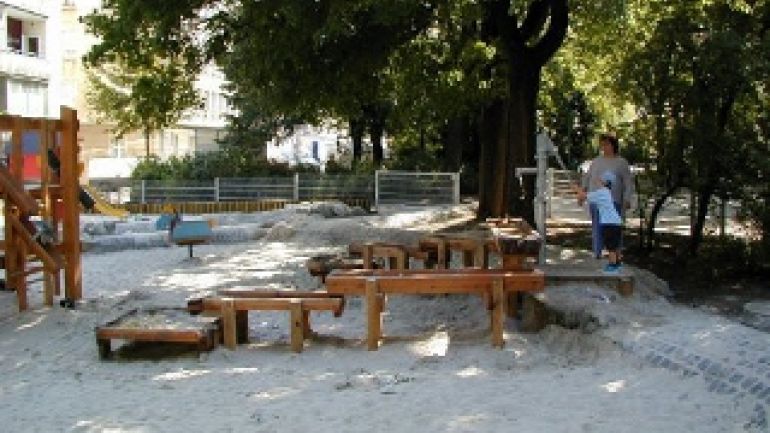 Kind bei Wasserspiel mit Sandmulde und Spielgeräte