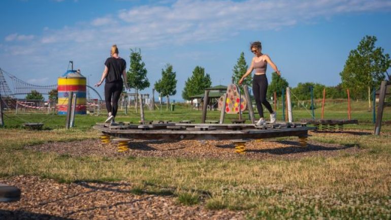 2 Frauen balancieren auf einem Gleichgewichtsgerät.