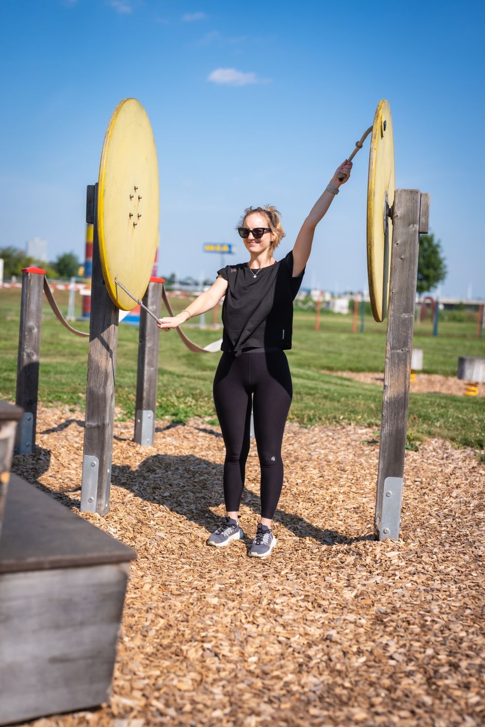 Eine Frau schwingt ihre Arme an Seilen, die auf Holzscheiben befestigt sind.
