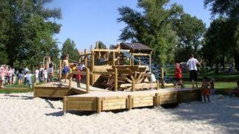 Klettergeräte aus Holz mit Mühlrad und spielenden Kindern