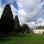 copyright: Wiener Stadtgärten Wiese mit Gebäude, hohe Bäume, Wolken am Himmel
