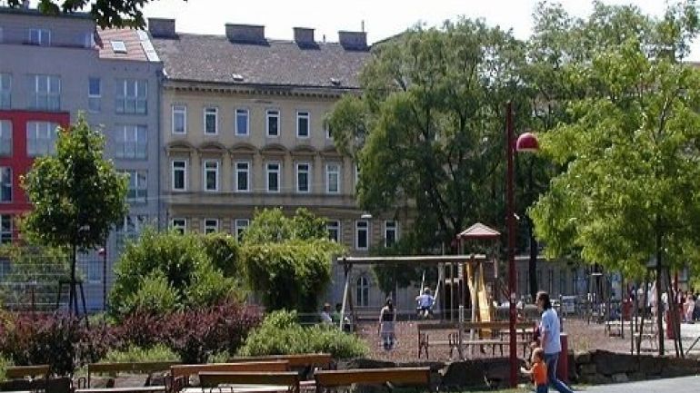 copyright: MA 42 eine Wiese mit Bänken, dahinter sind Bäume und Sträucher sowie ein Spielplatz