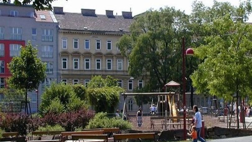 copyright: MA 42 eine Wiese mit Bänken, dahinter sind Bäume und Sträucher sowie ein Spielplatz
