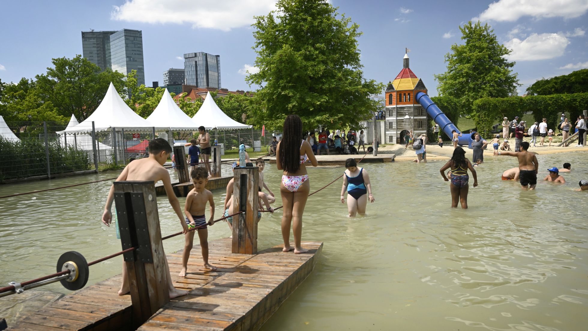 Kinder auf Floßen und im seichten Wasser stehend