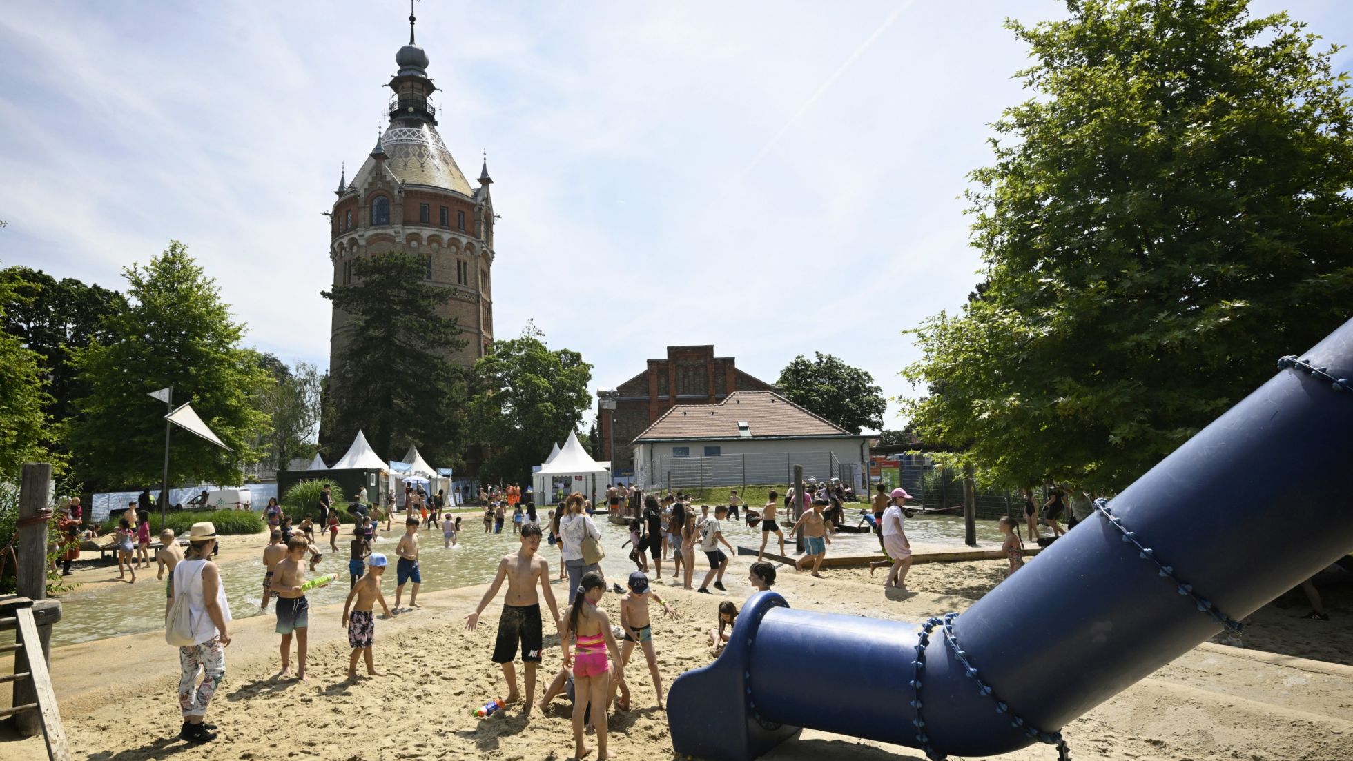 Sandspielplatz mit Rutsche, im Hintergrund Wasserturm
