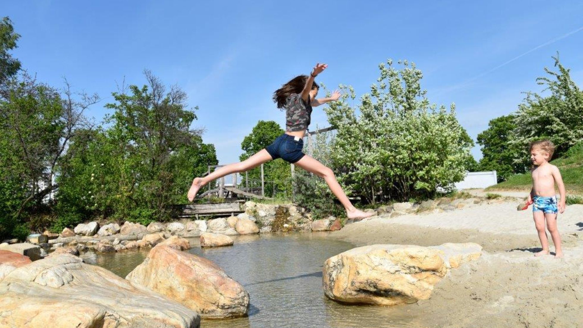 Mädchen springt über einen Bach
