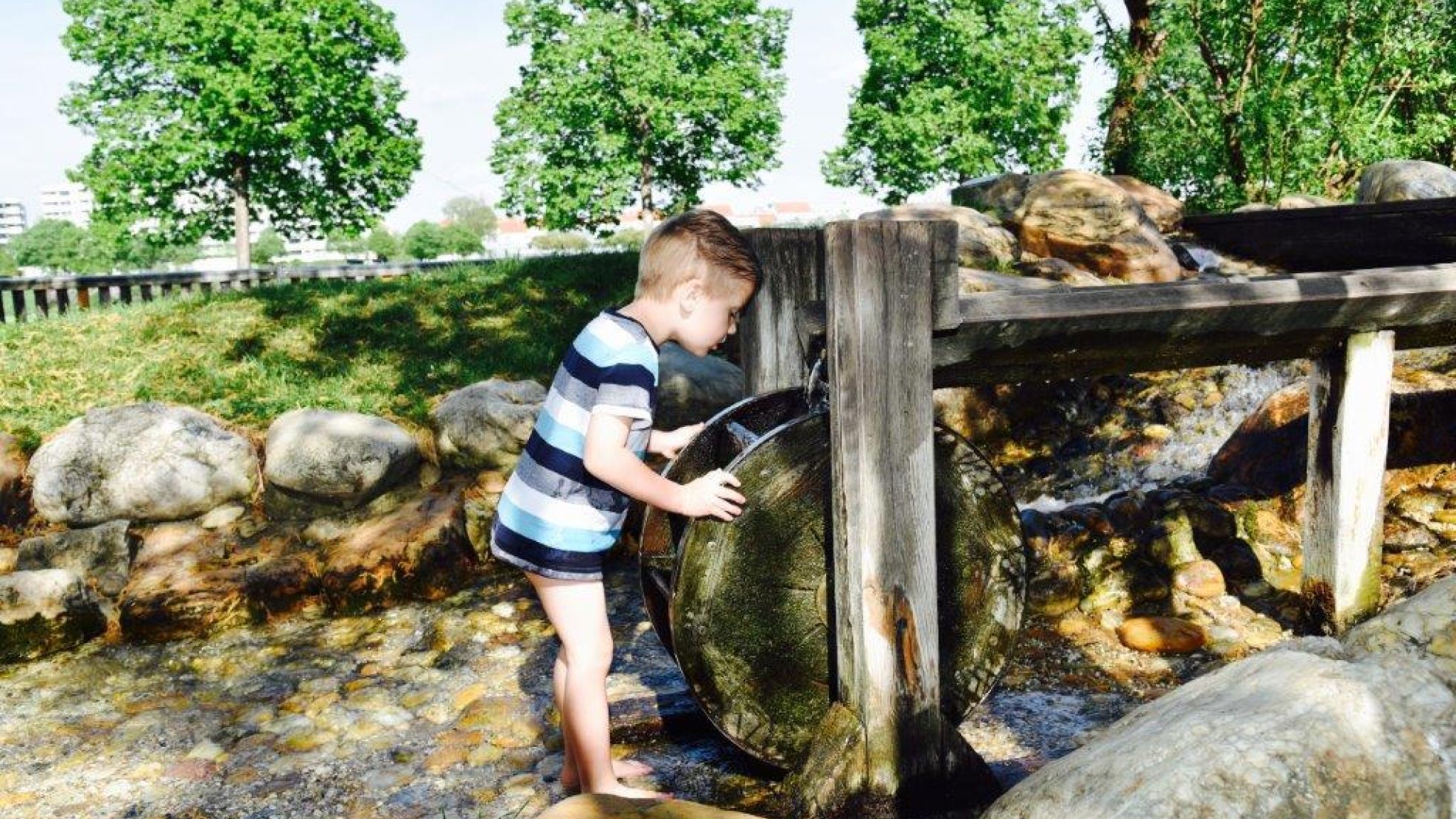 Kleinkind spielt mit einem Mühlrad aus Holz