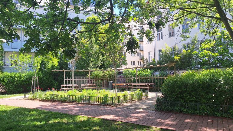 Park mit Sitzmöglichkeiten neben einem Stauden- und Gräserbeet.
