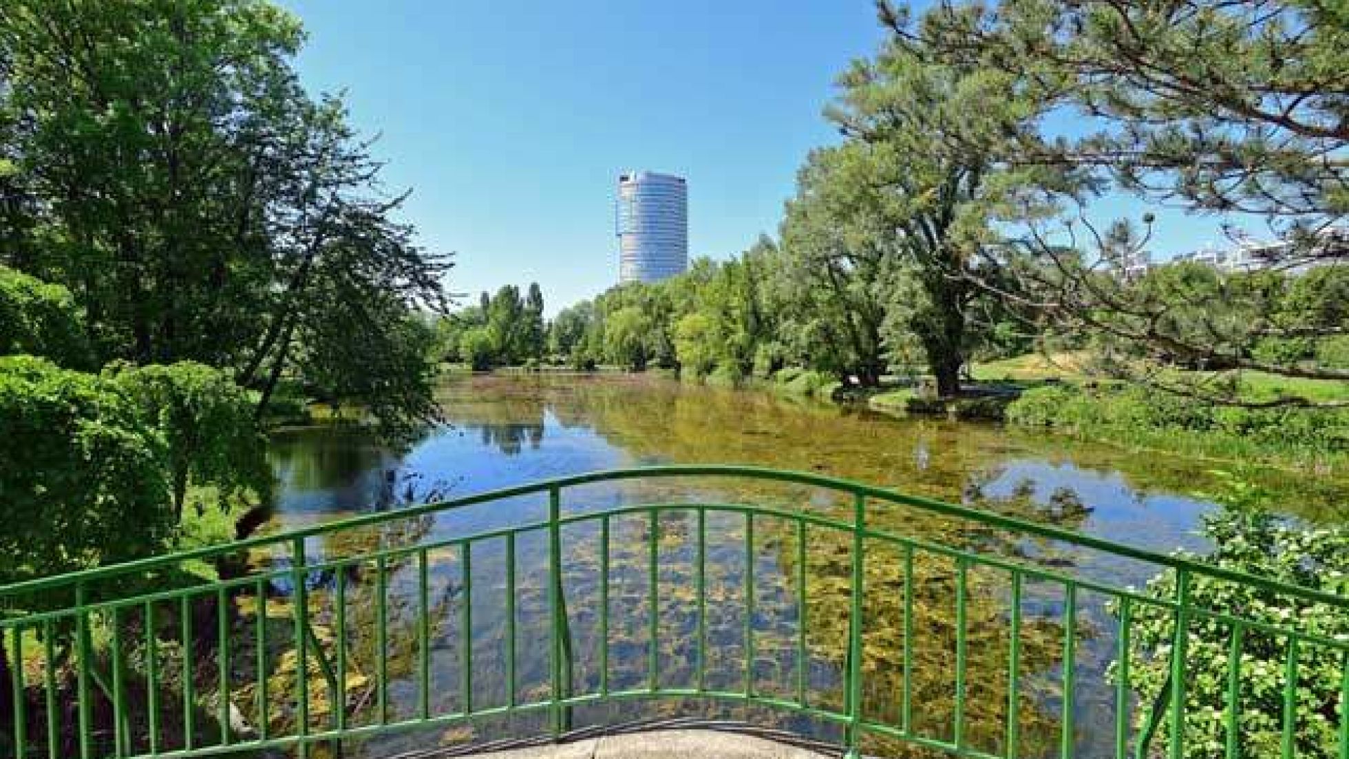 Teich in einem Park, im Vordergrund eine Brücke