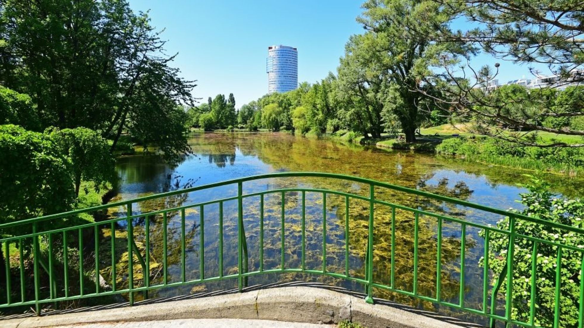 Teich in einem Park, im Vordergrund eine Brücke
