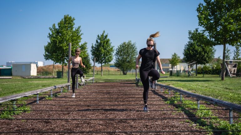 2 Mädchen laufen auf einer Laufstrecke, über die Seile gespannt sind