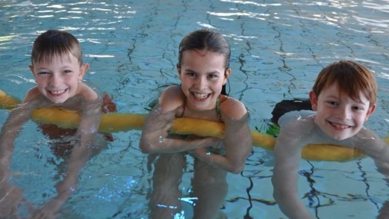 copyright: Stadt Wien - Bäder Kinder schwimmen mit einer Schwimmnudel im Wasser