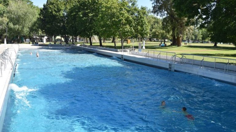 Schwimmbecken im Freien mit wellendem Wasser, rundherum Bäume