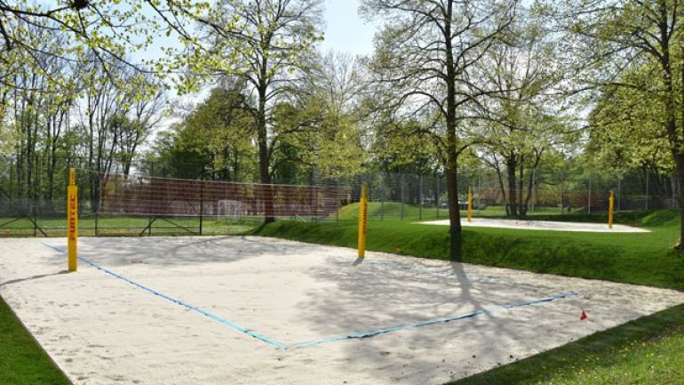 Volleyballplatz mit Sand und Netz, im Hintergrund ein weiterer Volleyballplatz