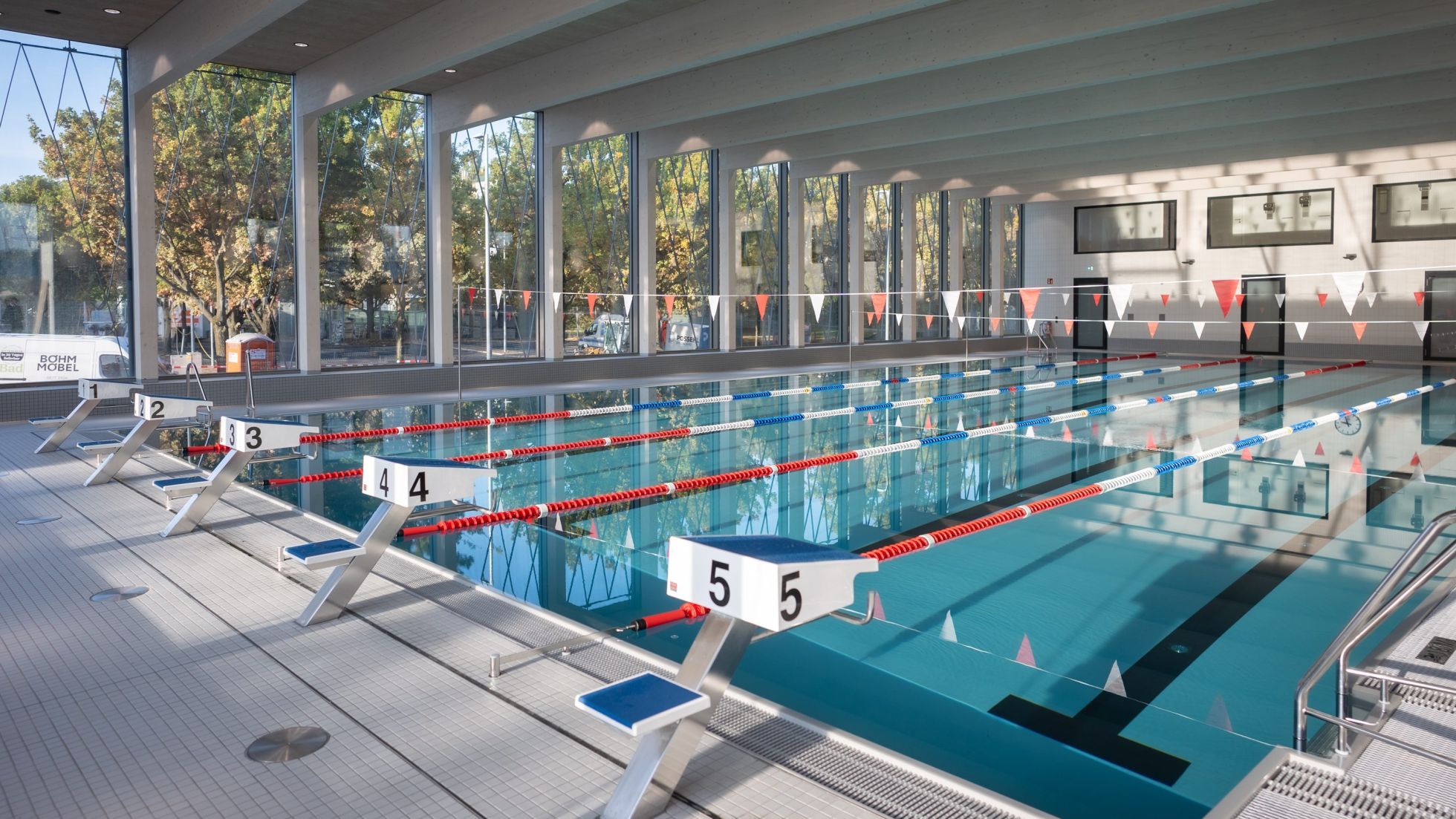 Moderne Schwimmhalle mit Schwimmbahnen und breiter Fensterfront.
