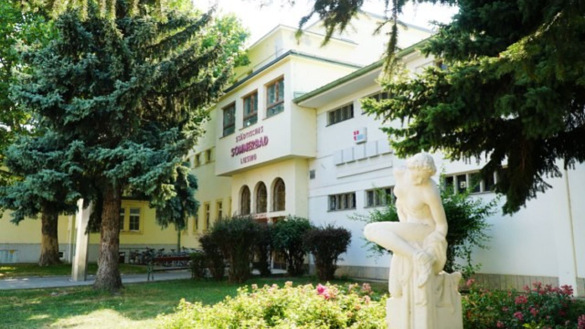 Eingangsbereich des Liesinger Bad mit einer Statue und Bäumen