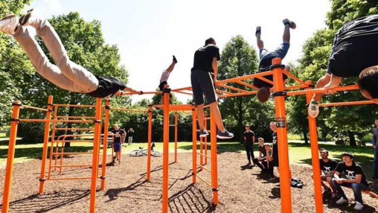 Junge Menschen trainieren auf einem orangen Klettergerüst.