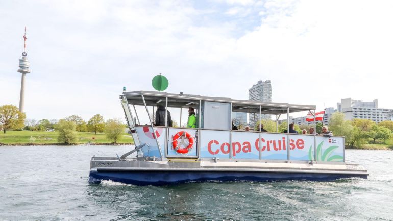 Fährbook auf dem Wasser, im Hintergrund der Donauturm