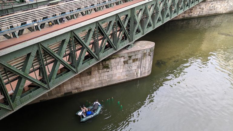 Zwei Männer in Schlauchboot bringen Laichbürsten unter Brücke aus